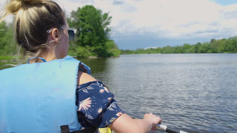 Stylish-young-woman-leisurely-rowing-a-canoe-down-a-river