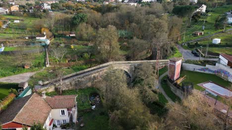 Drone-orbits-around-lonia-river-triangular-bridge-with-large-wide-opening-in-Ourense-Spain