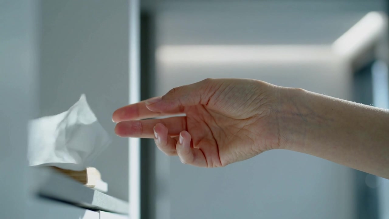 Reaching right hand pinching and pulling tissue from low cabinet dispenser, bare forearm visible