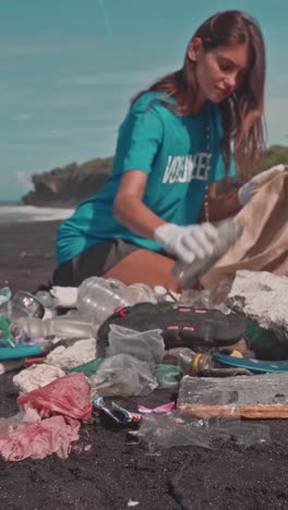 young beautiful smiling caucasian woman puts garbage in bag kneeling on beach