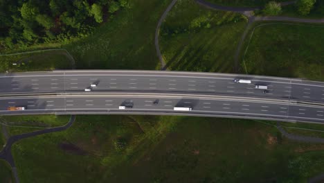 Blick-Auf-Eine-Drohne,-Die-Vertikal-Nach-Unten-Fliegt-Und-Eine-Autobahn-Beobachtet,-Auf-Der-Viele-Fahrzeuge-Sie-überqueren,-Die-Güter-Auf-Einer-Deutschen-Straße-Transportieren