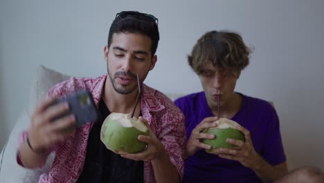 two young men taking a selfie and enjoying coconut drinks