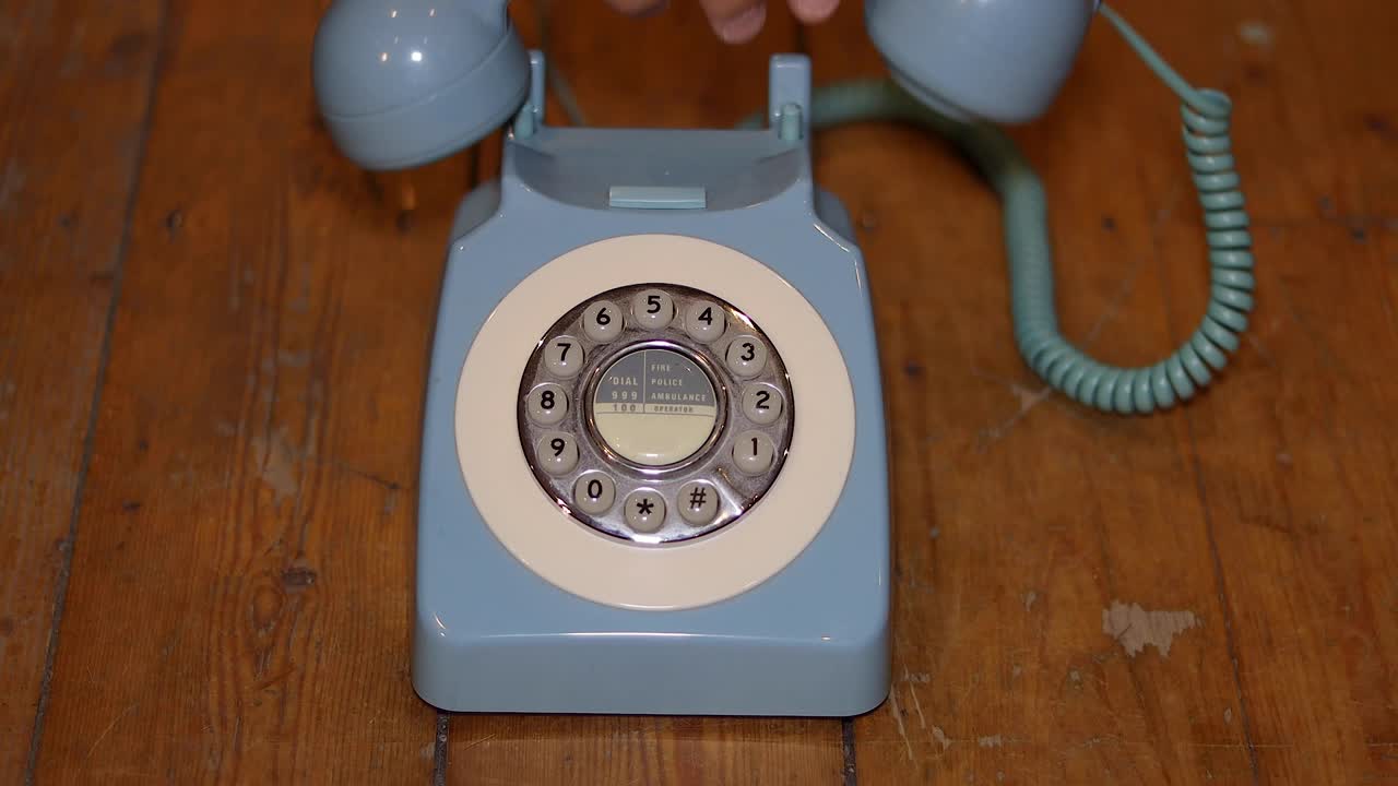 An old telephone on a wooden background with a male picking up the phone and hanging it up.