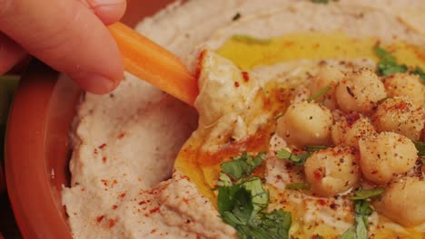 hummus among fresh vegetables on table close-up. hummus garnished with chickpeas, olive oil, spices and greens. hummus or fava, a hearty snack of legumes. kosher healthy vegan food. lean, vegetarian dish