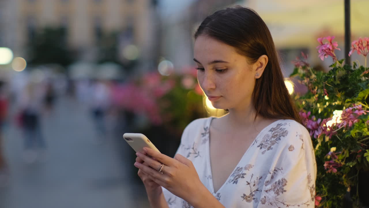 joven usando un teléfono inteligente en una calle de la ciudad por la noche