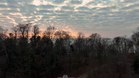 Es-Erhebt-Sich-über-Die-Baumgrenze-Und-Zeigt-Den-Sonnenuntergang-über-Dem-Nahegelegenen-See