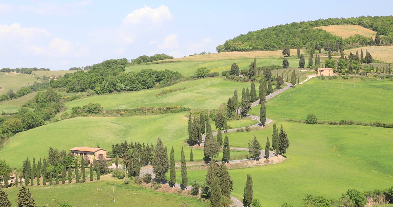 Una strada tortuosa fiancheggiata da cipressi in Val d'Orcia, Toscana, Italia. Designata Patrimonio dell'Umanità dall'UNESCO, la Val d'Orcia è un paesaggio di estetica distintiva e pianure gessose