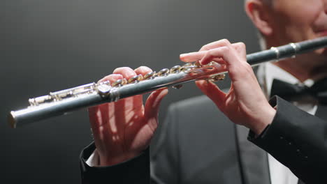 músico está tocando la flauta en la ópera o en el salón de música moderna primer plano de manos masculinas con la flauta