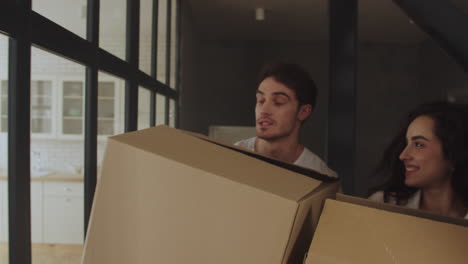 Closeup-couple-moving-to-new-apartment-with-paper-boxes-in-slow-motion.