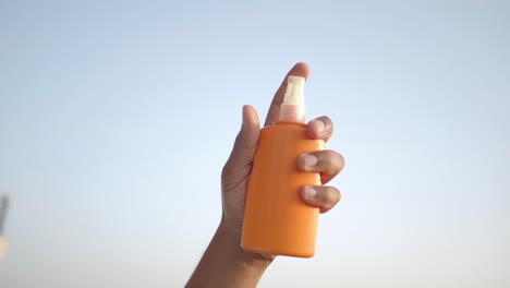 mano con una botella de protector solar en aerosol