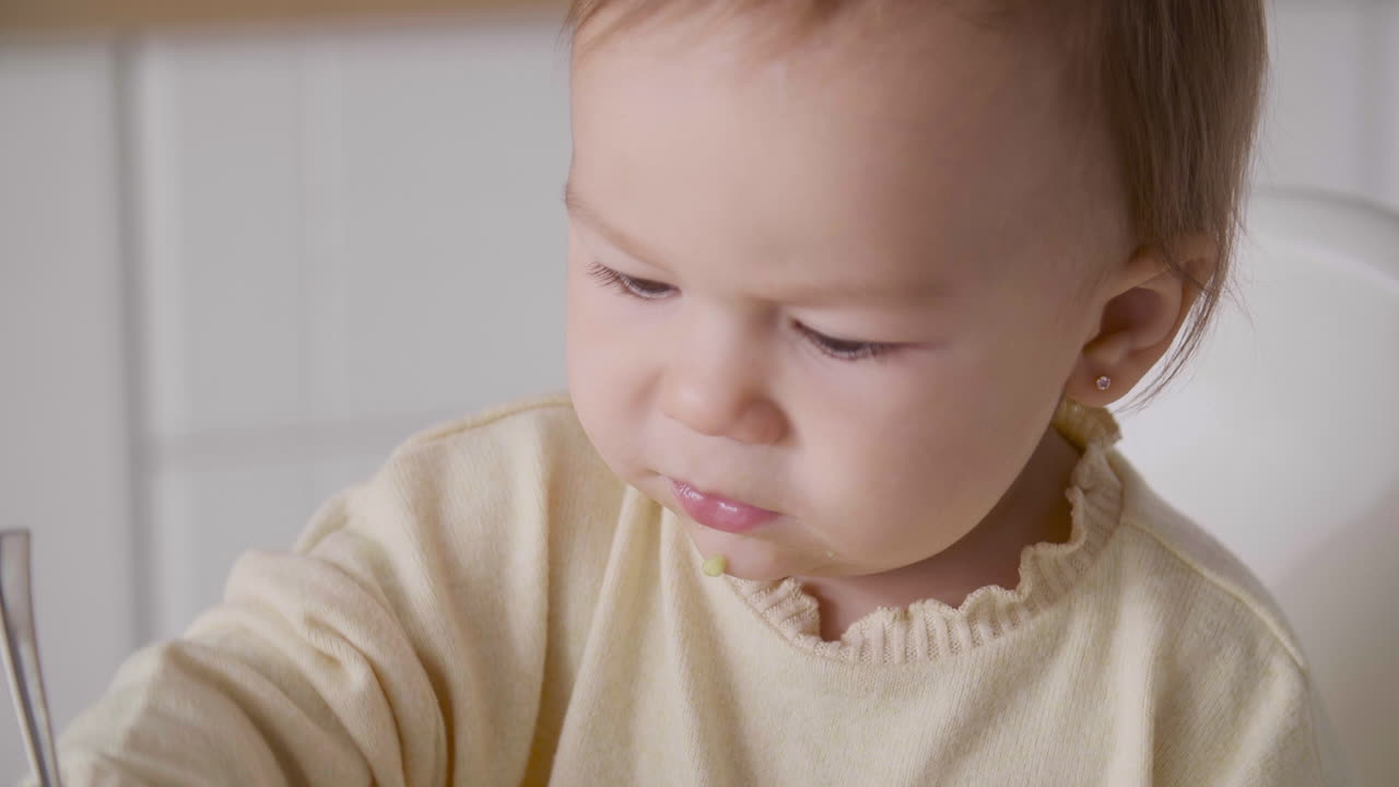 부엌에 있는 높은 의자에 앉아 지저분한 얼굴을 가진 귀여운 여자 아기를 닫습니다