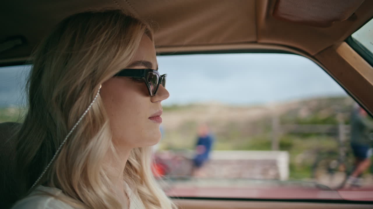 Attractive lady driver riding auto in sunglasses closeup. Girl driving highway