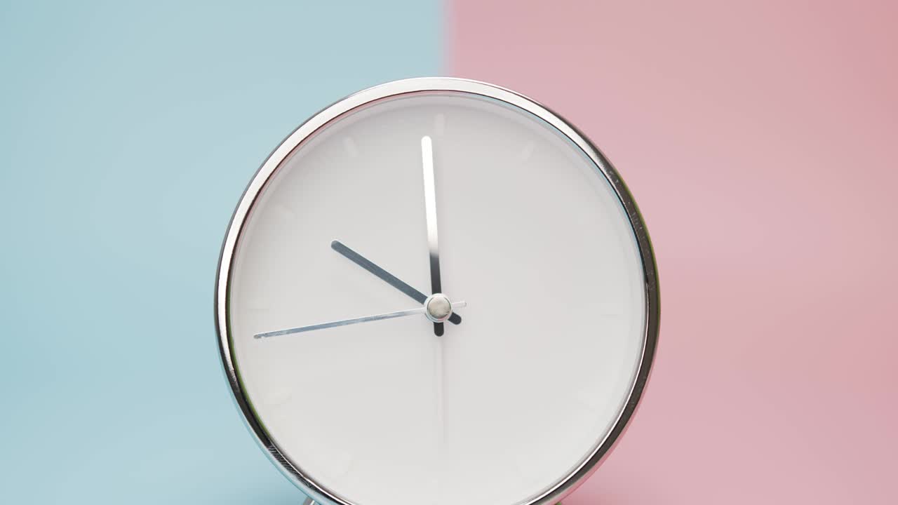 reloj de plata aislado sobre un fondo rosa azul.