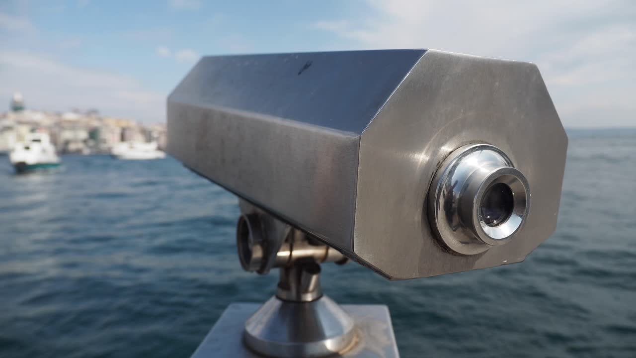 un primer plano de un telescopio operado con monedas de plata con vistas a un puerto