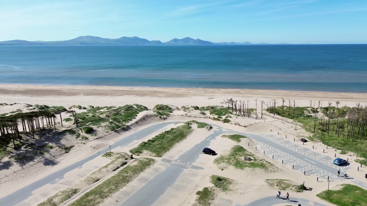Newborough beach aerial view towards sunny woodland car park coastline and Snowdonia mountain range