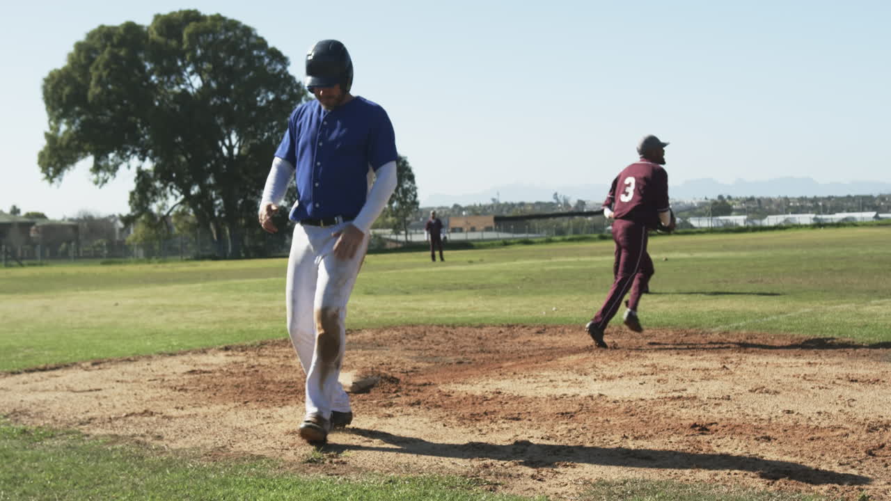 Giocatori di baseball multietnici che festeggiano e si abbracciano su un campo da baseball, al rallentatore