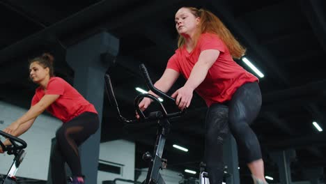 grupo de chicas atléticas realizando ejercicios de entrenamiento de equitación aeróbica en bicicleta estacionaria en el gimnasio