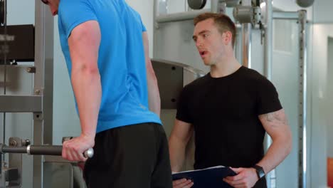 fit man doing pull ups with trainer