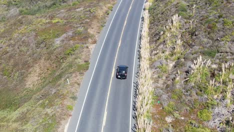 video aéreo de una autopista, un coche negro conduciendo, la cámara se levanta, en la costa de pescadero, san mateo california