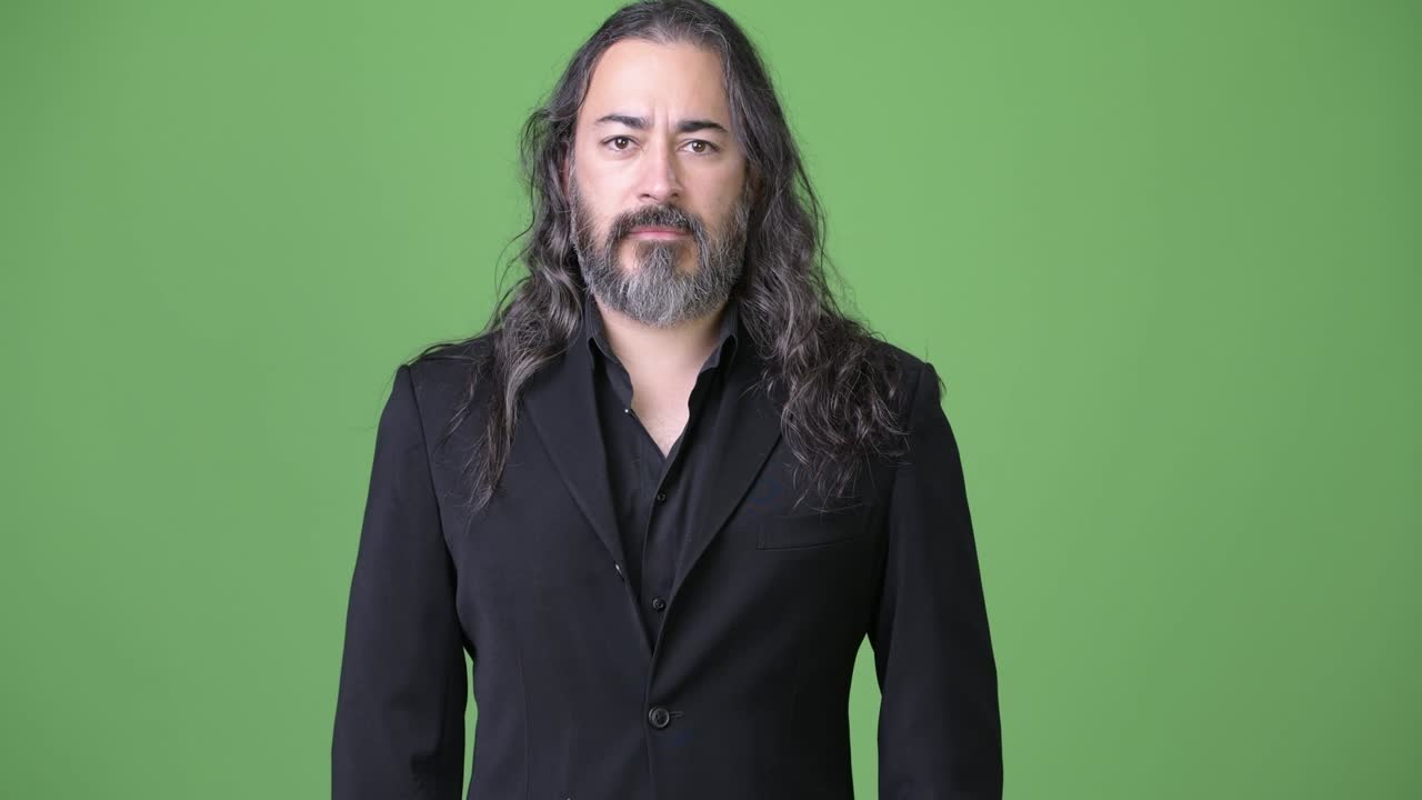 Studio shot of mature handsome bearded multi-ethnic businessman with long hair