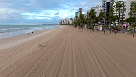 Aerial of Boa Viagem Beach, Recife, Brazil. Sand, blue green sea, beachgoers, buildings, and pigeons in early morning.