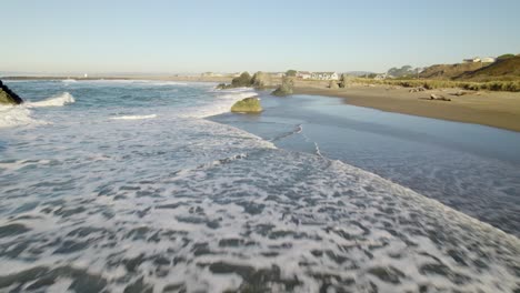 4k scenic aerial drone shot gliding over waves at bandon, oregon beach
