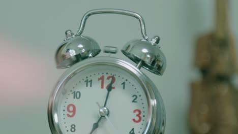 old fashioned alarm clock rings in the morning on a table . girl’s hand overturns the alarm so that it shuts up . sleeping girl waking up from alarm calling and turning it off . classic clock ringing