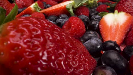 macro-view-passing-over-a-selection-of-berries-on-black-background,-4k-shot-of-healthy-fresh-fruit,-nutritional-diet,-blueberries,-raspberries-and-strawberries