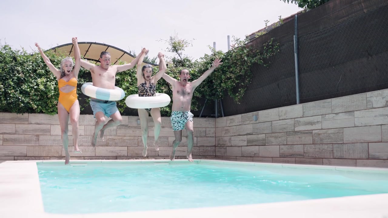 Group of Friends Jumping into Swimming Pool with Inflatable Rings
