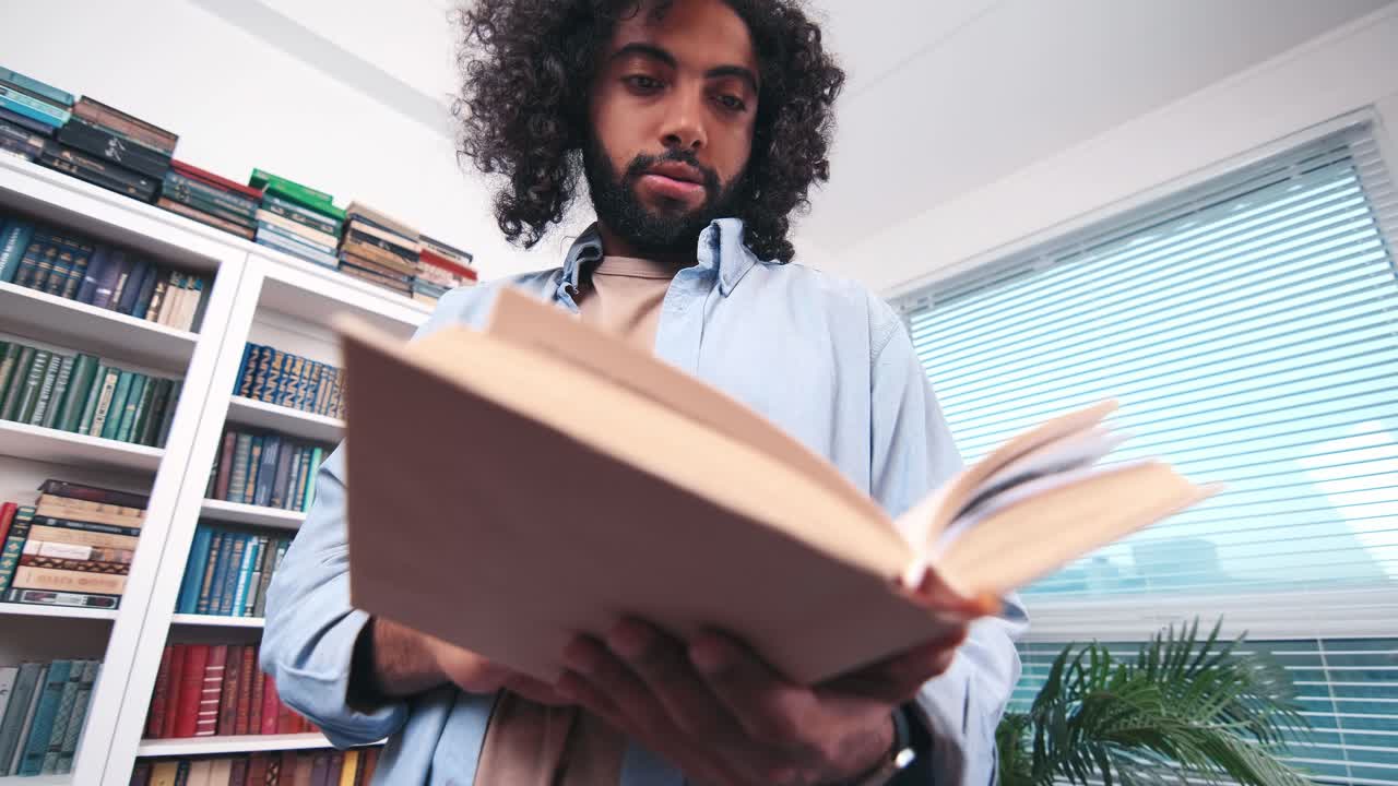 Carried away young inquisitive indian man stands with open book in hands