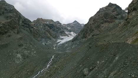 Aerial-View-Of-Mountain-Hike-With-Flowing-Stream-At-Alpe-Ventina-In-Chiesa,-Valmalenco,-Sondrio-Province,-Italy