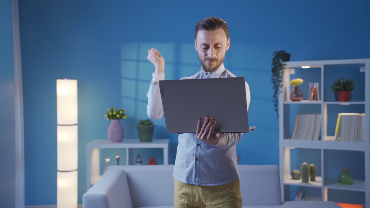 hombre adulto elegante, carismático y elegante que se divierte felizmente y baila de pie usando una computadora portátil.