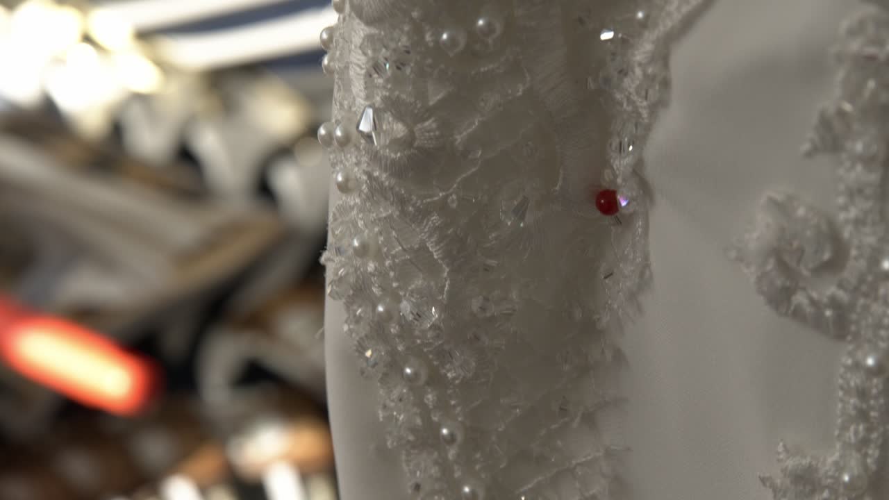 Intricate close-up of pearl adorned wedding dress fabric in bridal store. Soft lighting highlights the delicate pattern and texture, perfect for elegant wedding themes