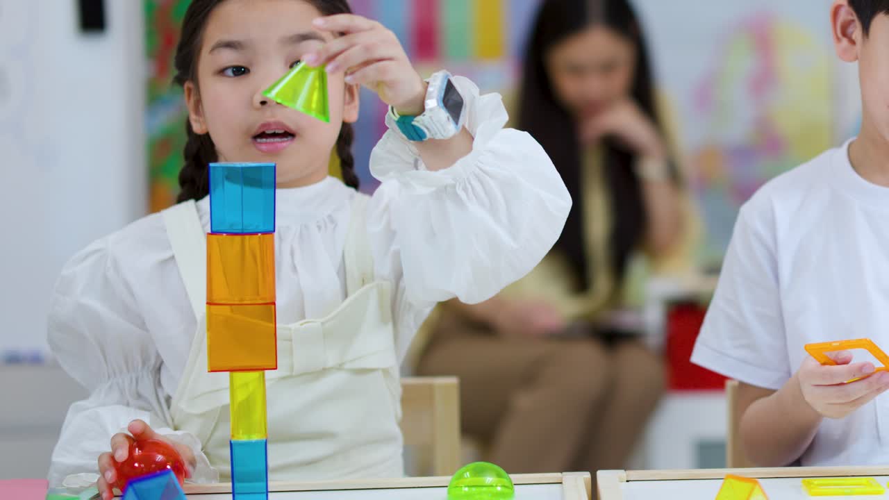 Two children construct creative shapes with colorful blocks in a bright, cheerful classroom setting