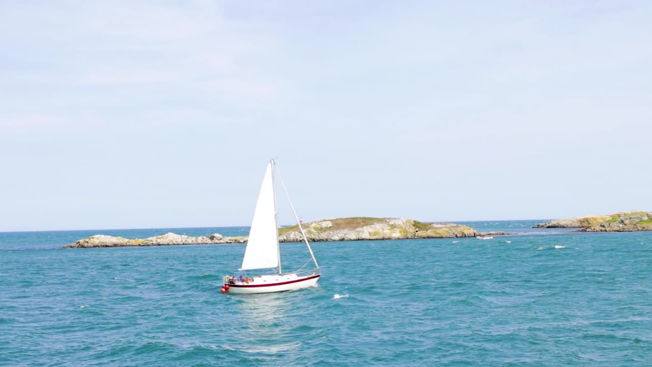 Dalkey Island is opposite Coliemore Harbour in Dalkey. On a sunny day, a sailboat tries to push through the waves