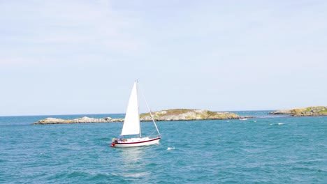 dalkey island is opposite coliemore harbour in dalkey. on a sunny day, a sailboat tries to push through the waves