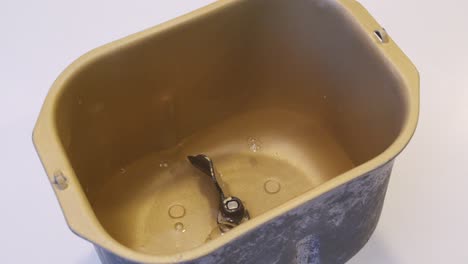 bread ingredients being put into a bread maker pan