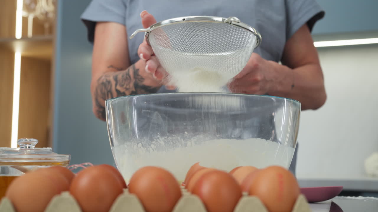 Woman sifting flour into a bowl to make a dessert recipe. Slow motion close up