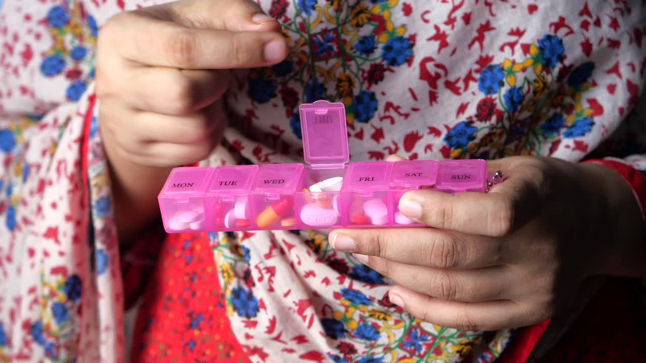 매일 약을 복용하는 여성은 약을 준비하는 장치를 가지고 있습니다.