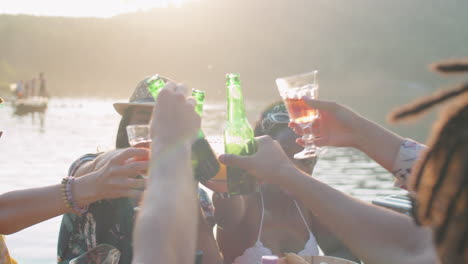 company of young friends toasting with drinks at lake party