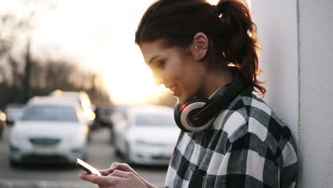 stunning view of the brunette girl in the rays of the setting sun, which writes a message on the mobile phone. smile. blurred background