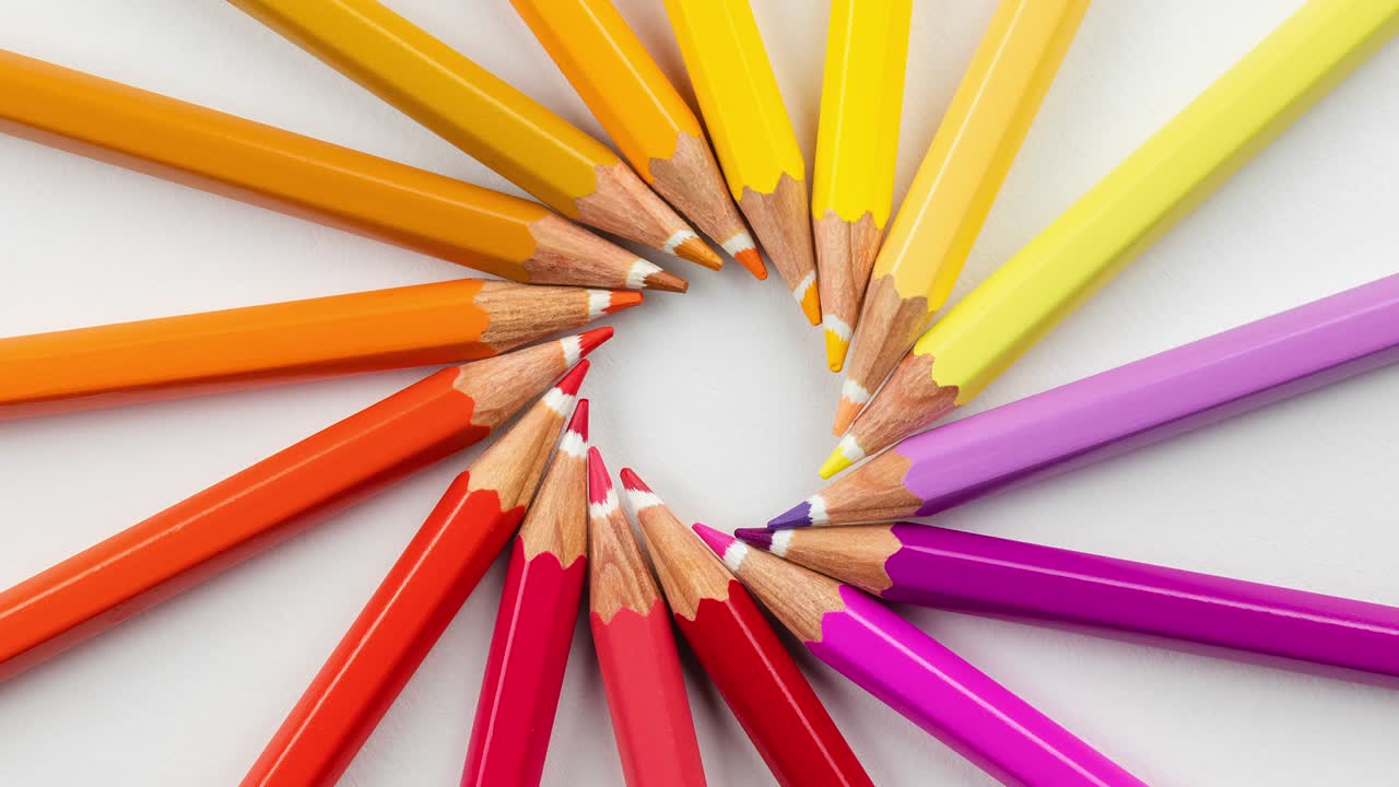 4K video. Creative layout made of colored wooden pencils on a white background. round flat lay composition, top view, copy space