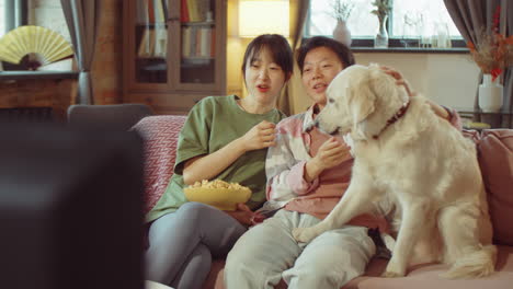 happy asian women and dog eating popcorn and watching tv at home