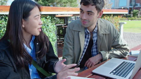 young man and woman having talk at outdoor coworking space