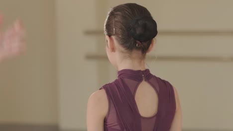 un grupo de jóvenes estudiantes de ballet con ropa de baile negra practicando posiciones en un amplio estudio de ballet con pisos de madera y barras montadas en la pared. expresiones enfocadas y movimientos sincronizados.