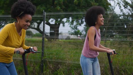 Two-mixed-race-women-riding-electric-scooter