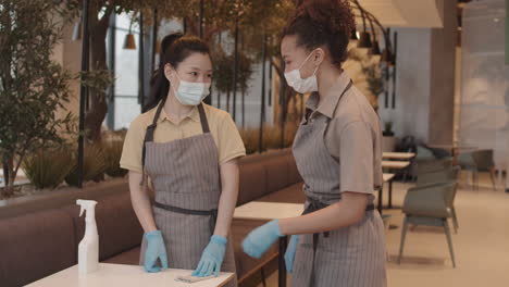waitresses in masks greeting and cleaning table
