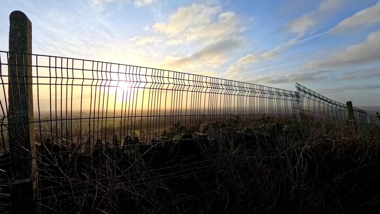 nubes doradas de amanecer paso del tiempo sobre tierras de cultivo cercadas de metal prado en la luz del día de la mañana