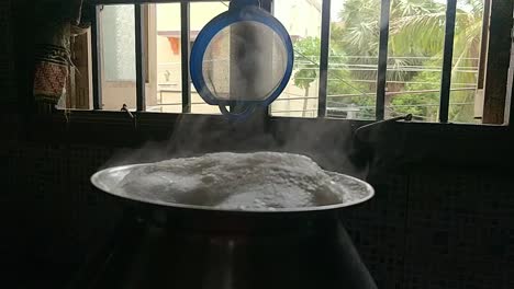 olla cocinando arroz de manera tradicional hirviendo agua en un fondo negro con humo blanco en cámara lenta