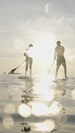 couple paddleboarding at sunset
